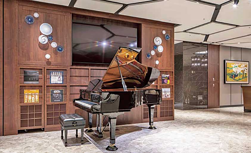 2階フロントロビーに配したノ自動演奏機能付きピアノ（YAMAHA | S6X-ENPRO）。ロビーフロアで定期開催される「サロン・コンサート」を客室の TVでもライブで体感できる