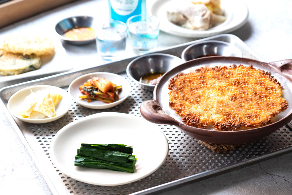 7月28日には“Frogs FARM ATMOSPHERE”で12軒目の出店となる、京都でビブグルマンを獲得した人気韓国料理店、「ピニョ食堂」オーナー全氏が監修する「きる かか」がオープンした。鶏の旨味が凝縮されたとろりとしたスープなど、辛くない、素朴な味わいの韓国料理が味わえる