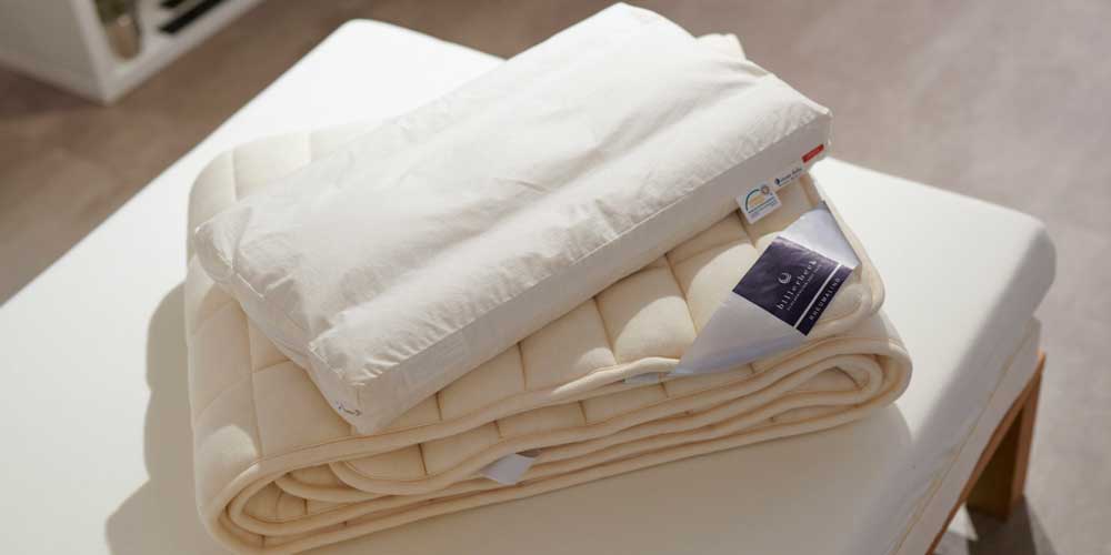 グッドナイトスリープルームの寝具。吸湿発散性の高い厚めの羊毛敷パッドと、暖かく吸湿性・発散性に優れたキャメルピロー