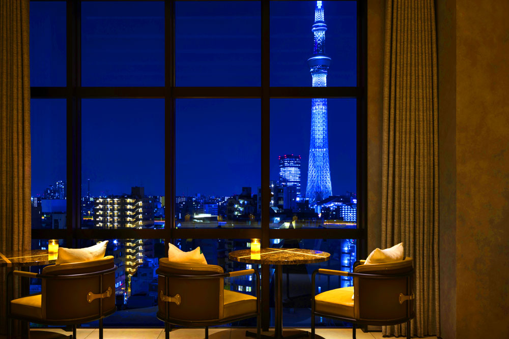 “OMOベース”から見た東京スカイツリーⓇの夜景。同サイドのスペースは各テーブルがゆったりとした間隔で置かれており、テラス席もあることからおちついた雰囲気でお酒や浅草の夜を楽しみたいお客さまのニーズにも適っている。反対サイドの窓からは浅草寺境内のライトアップを観ることもでき、気分によって席を変えるのも楽しい
