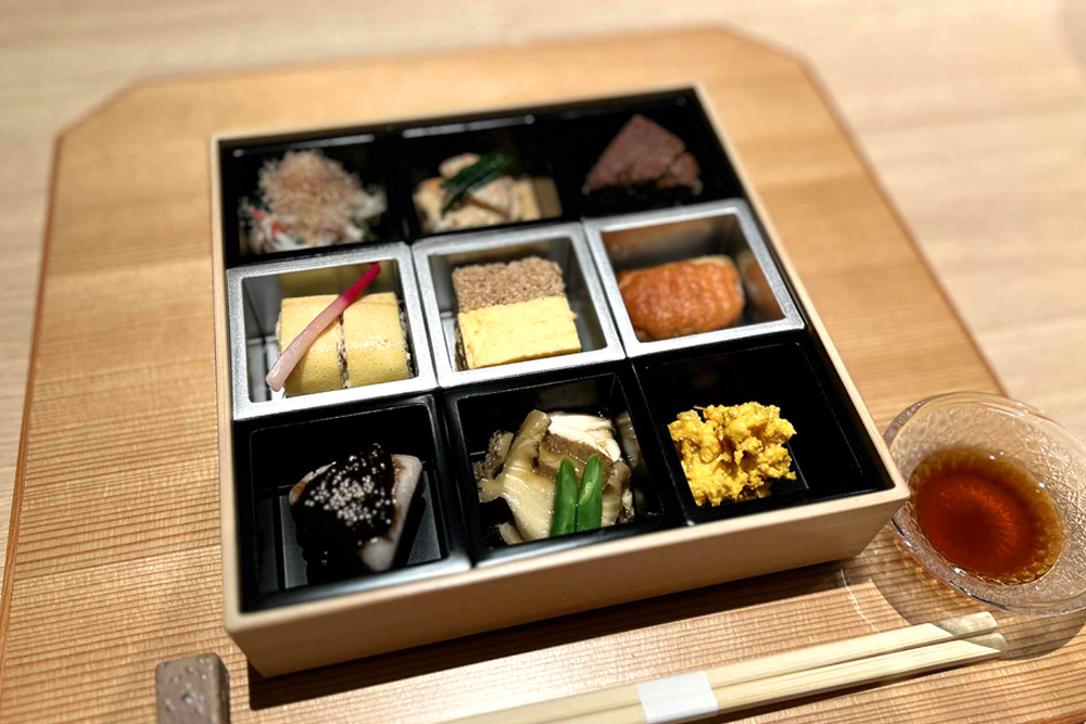 お重にミニ枡を遊彩箱のように見立てた演出で提供される前菜。“くわい豆腐”や“穴子寿司錦糸巻き”、“黒豆カステラ”に“カジキマグロ明太焼き”など、職人の技が光る美味を少しずつ。贅を凝らした一品一品に、季節の華やぎが活かされている
