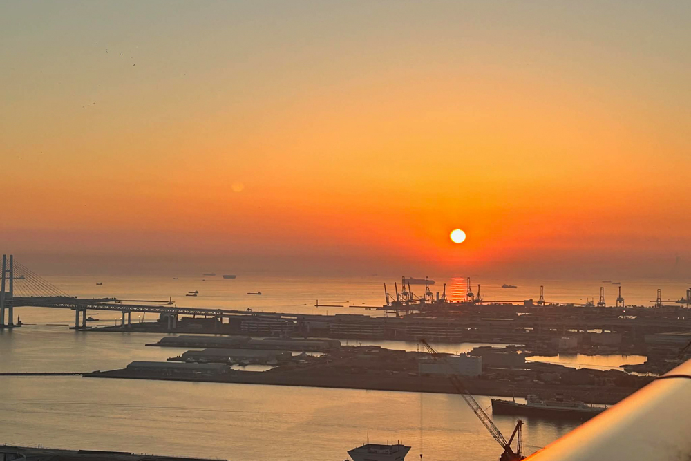 同客室から望む朝日。だるま朝日のように熟れた柿色に染まり、夕景を思わせる色味で静かに一日の始まりを告げる。島旅で目にするような印象的な朝景を、都心にいながらにして望めるのも、同所に宿泊する魅力のひとつだ